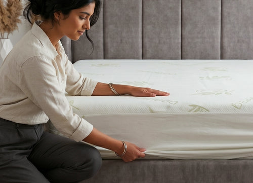 Woman fitting Morning Owl Bamboo Mattress Protector on bed showing soft breathable bamboo fabric cover India