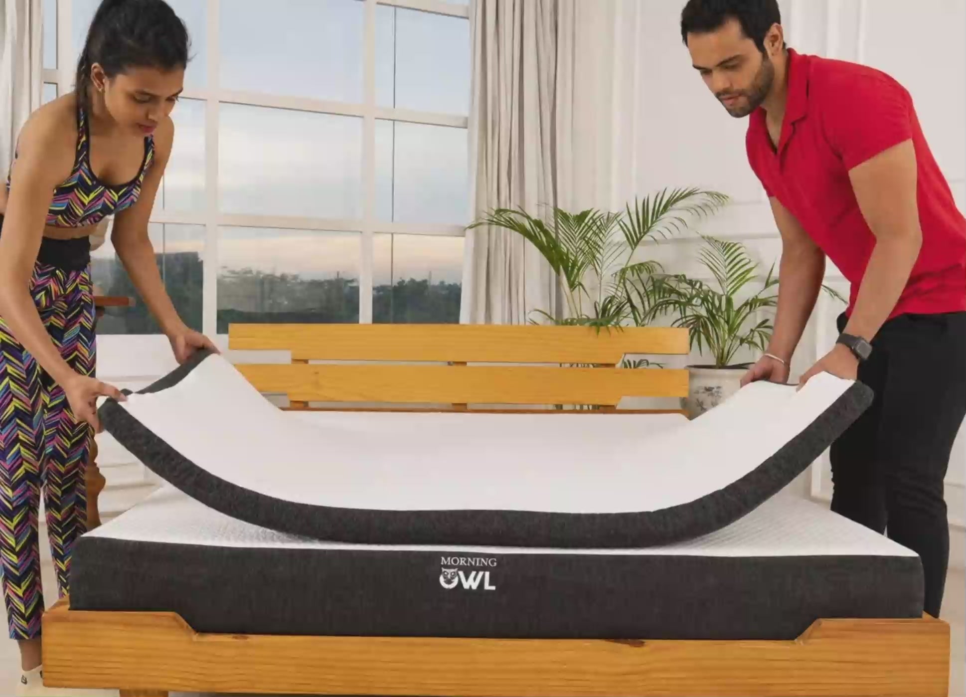 Two people placing a Morning Owl mattress topper on a bed.